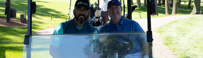 Two men sitting in a golf cart